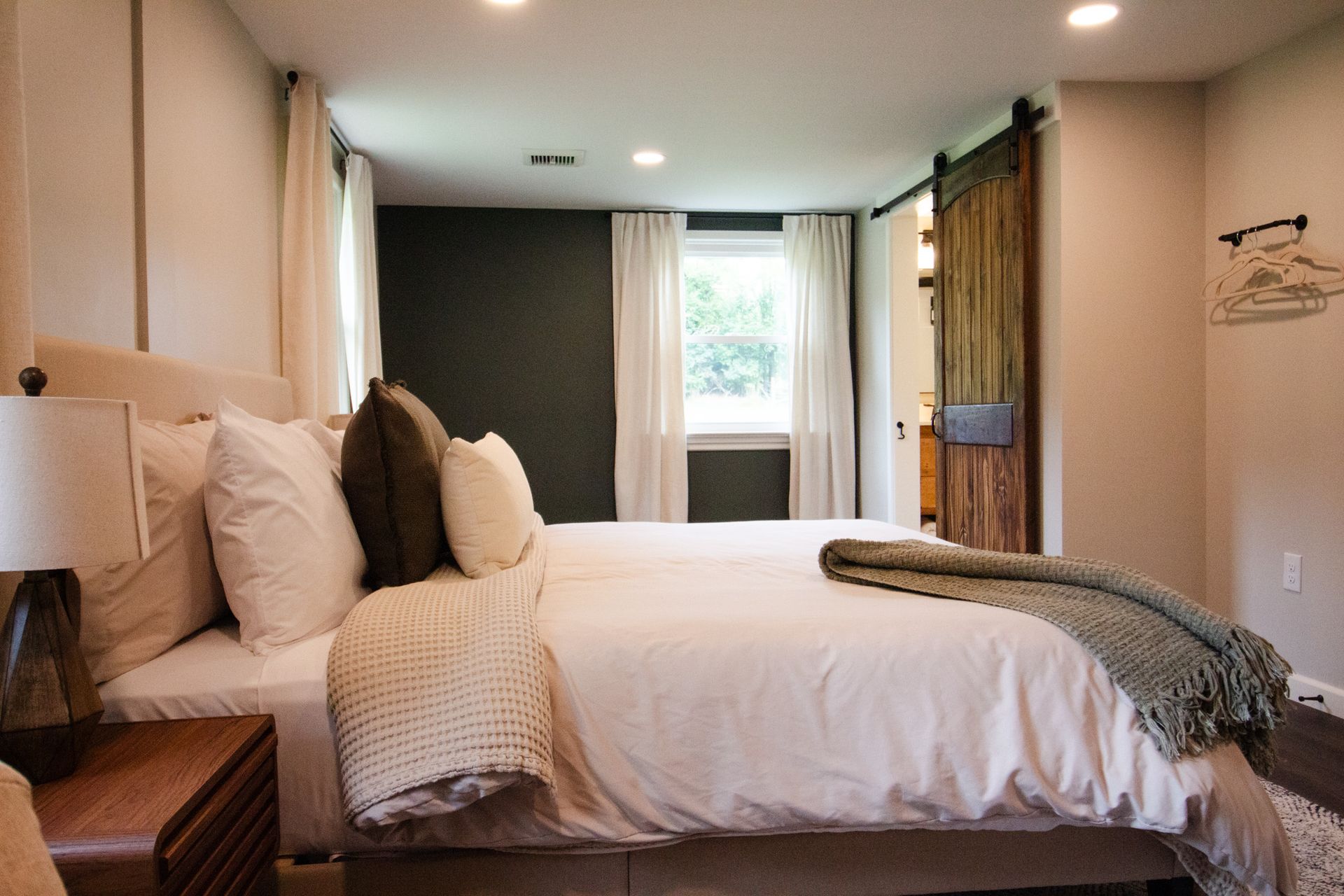 A bedroom with a large bed and a sliding barn door.