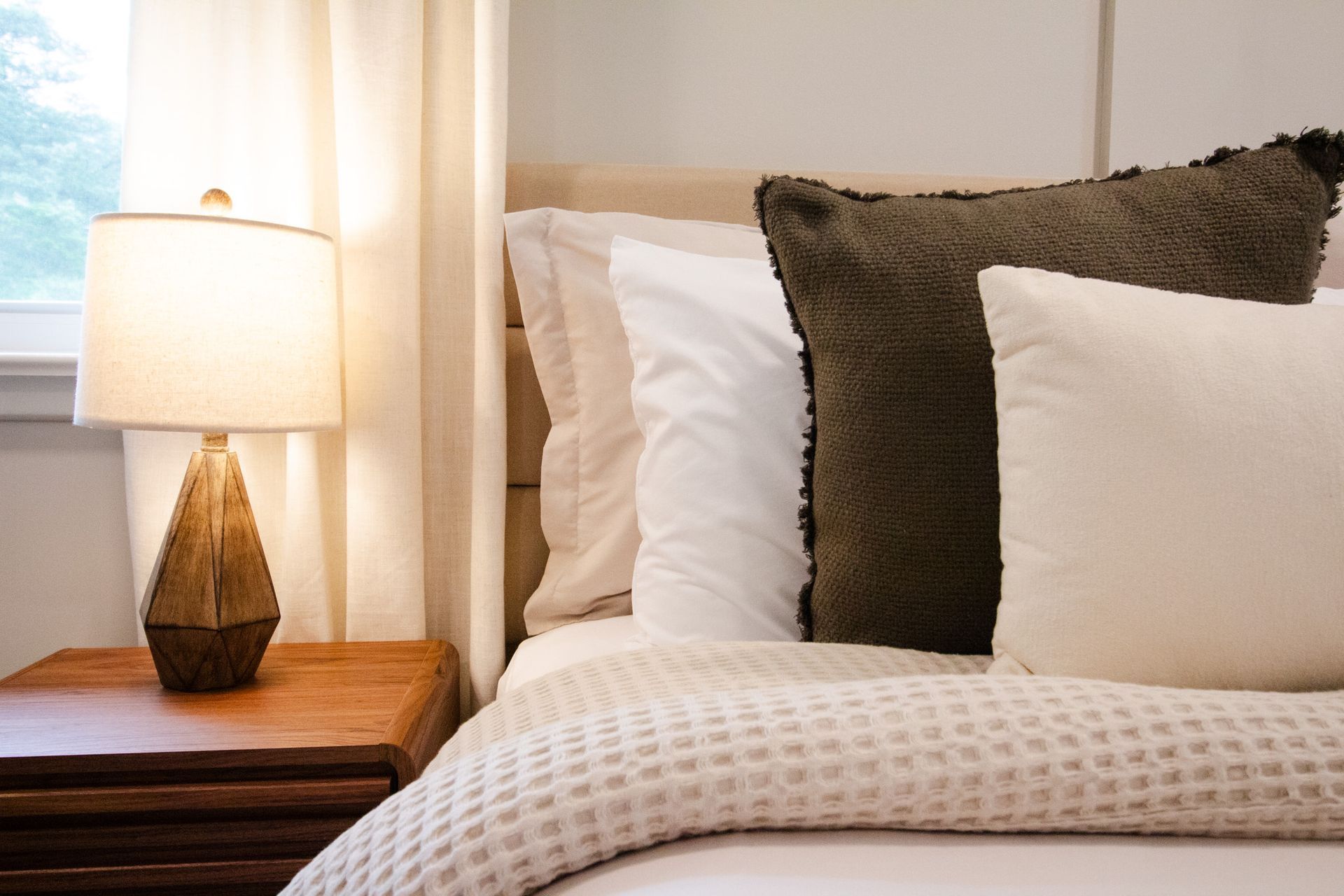 A bed with pillows and a lamp next to it