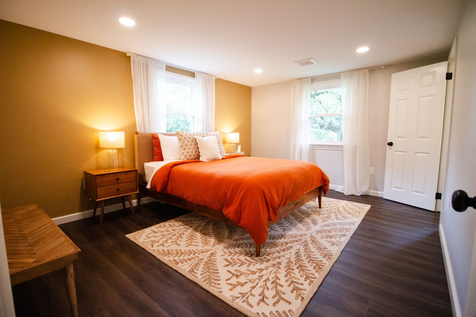 A bedroom with a bed , nightstand , rug and window.
