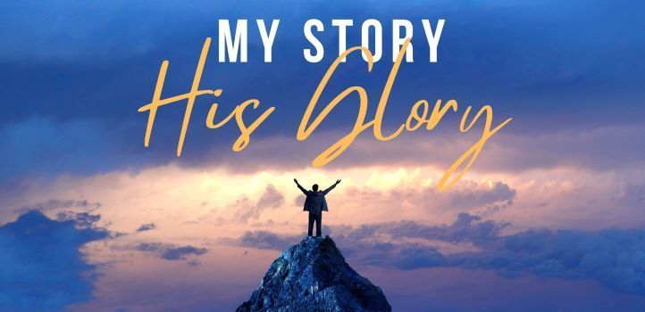 Man on top of a mountain with arms raised in worship.