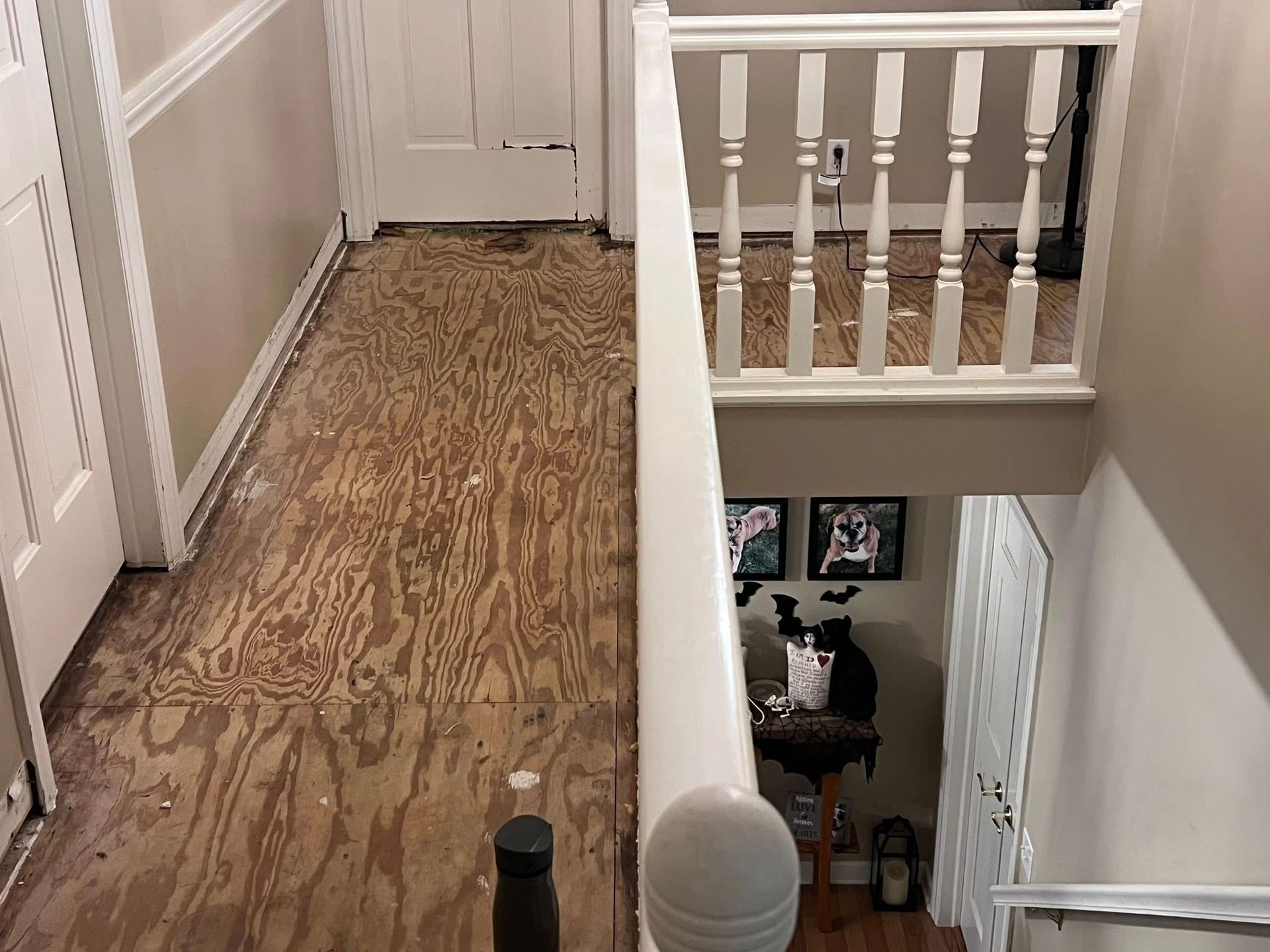Upstairs hallway with wood floor and white railing overlooking a staircase and lower room