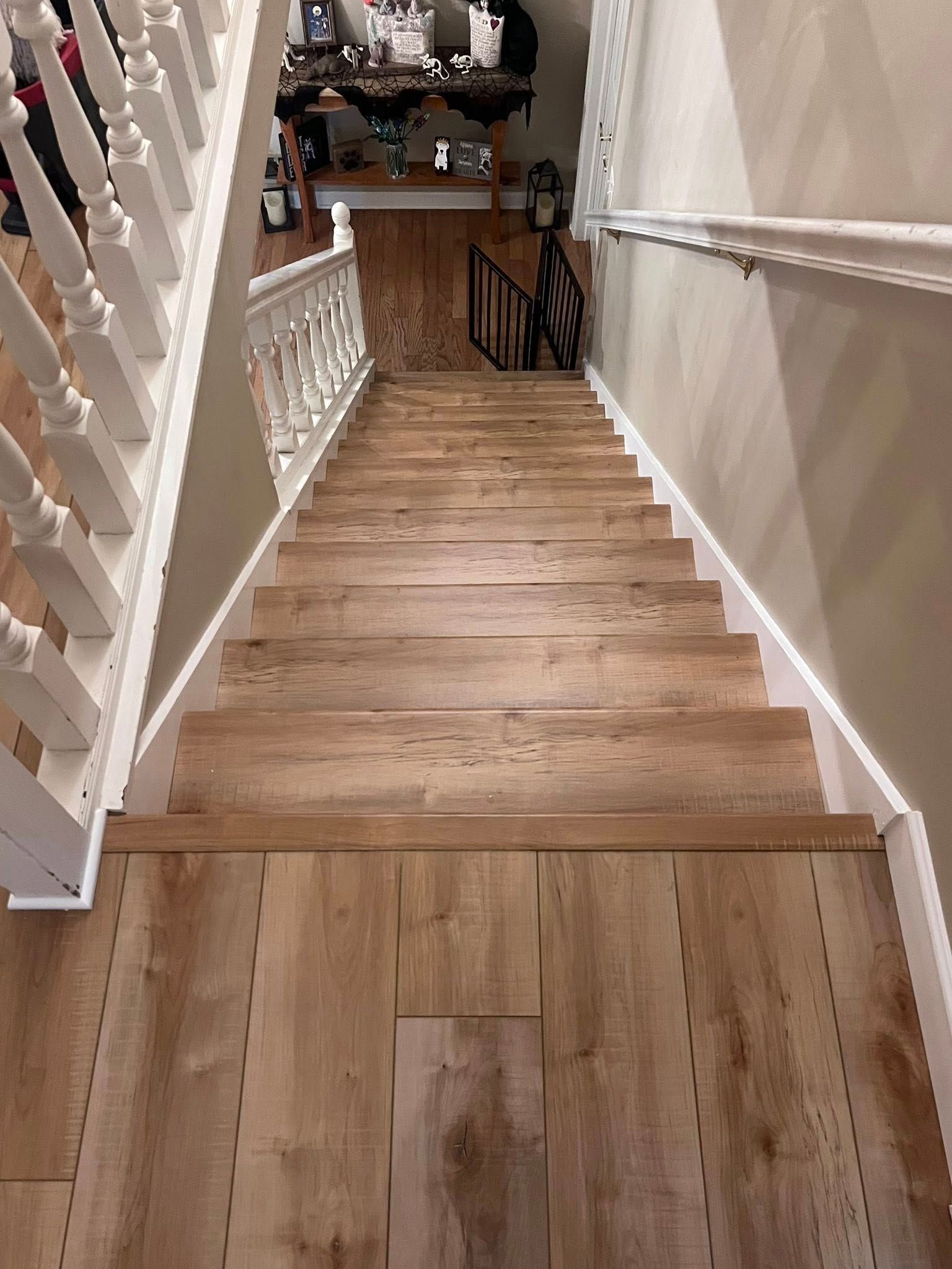 Wooden staircase descending into a warmly lit interior hallway with white banisters and wall molding