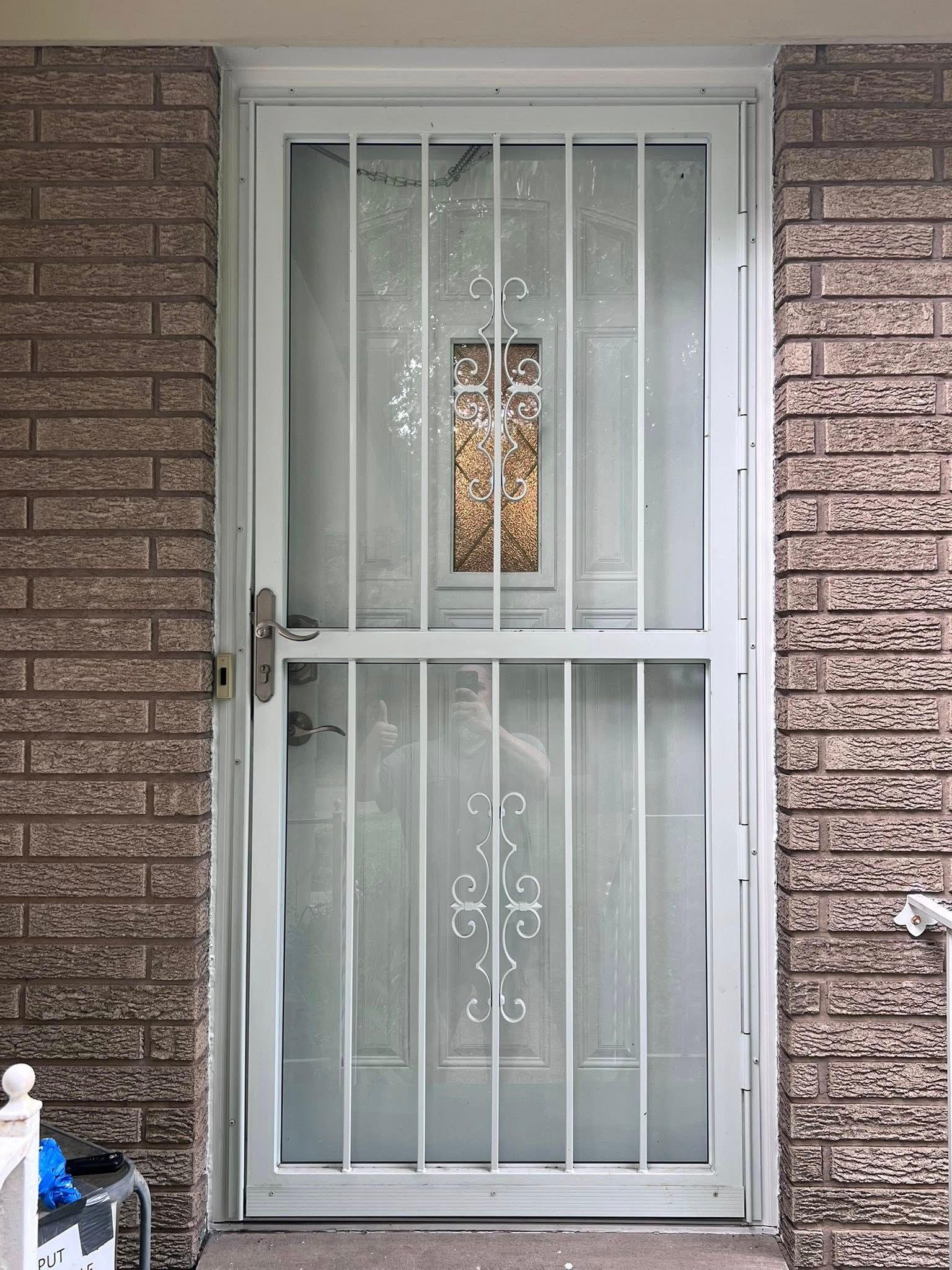 White metal security door set in a brick exterior wall with frosted glass panels.