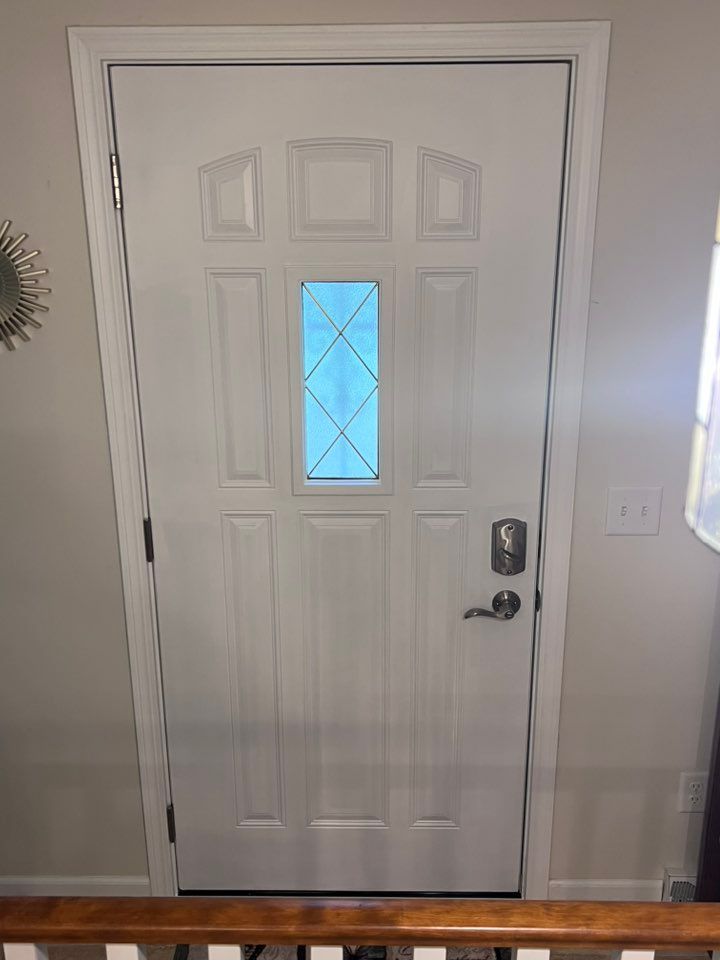 White front door with a small blue frosted window and silver handle in a home entryway