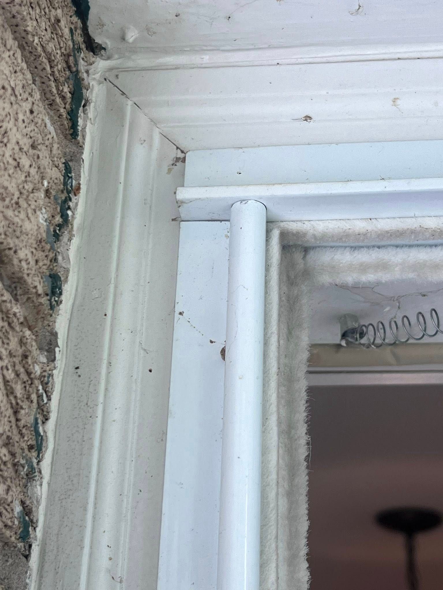 White door frame and trim with a vertical strip of weatherstripping beside a rough stone wall