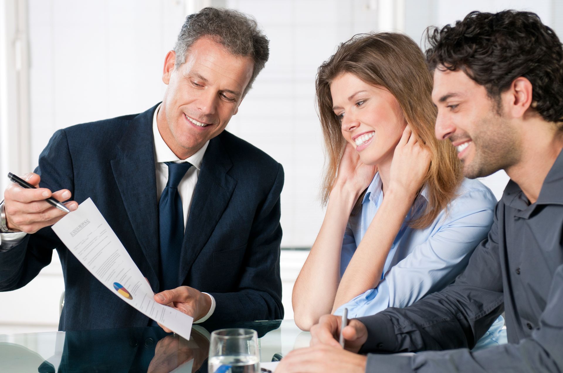 A man in a suit and tie is talking to a man and woman.