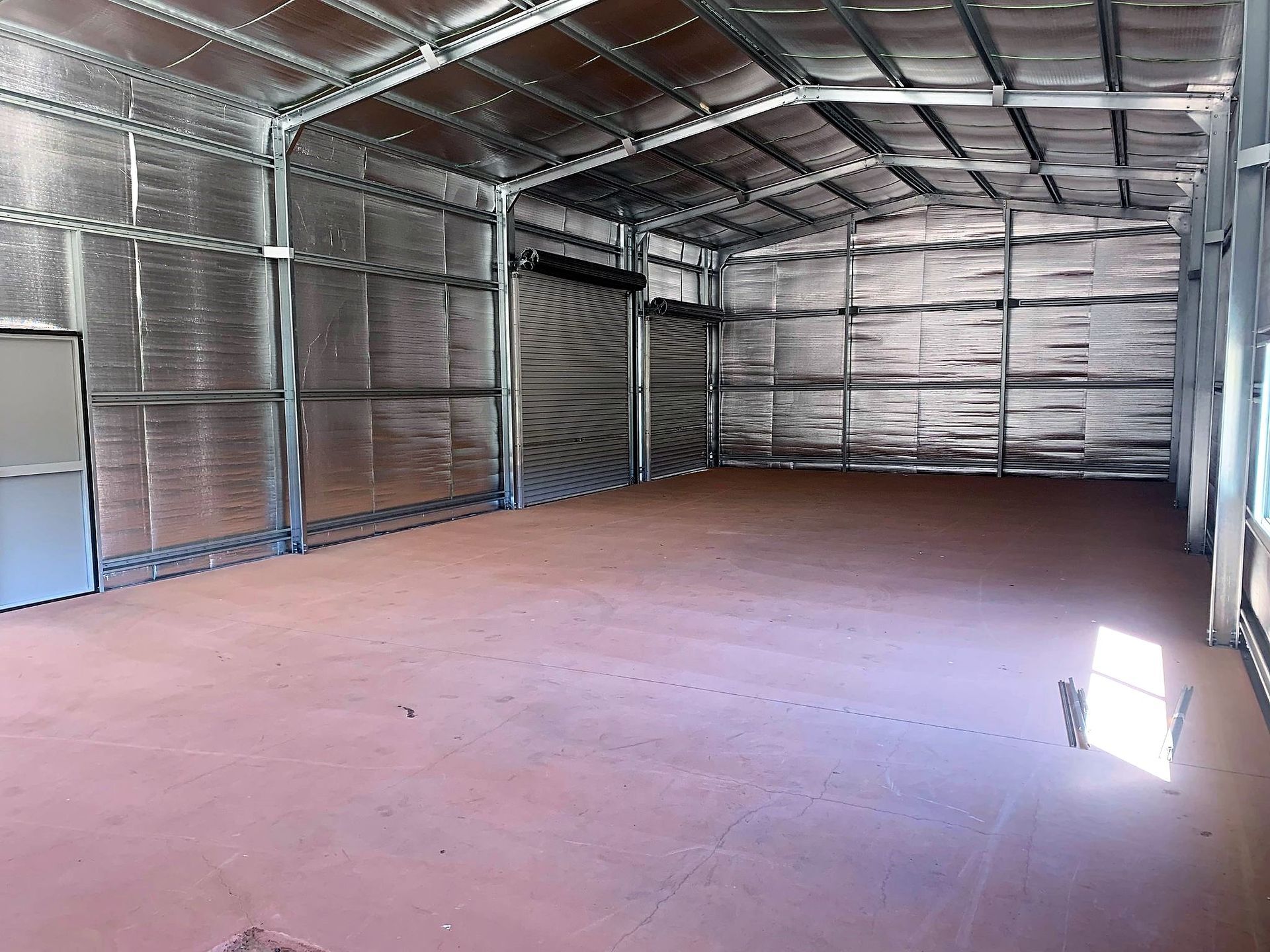 A farmland employee walking between cowshed rows inside a large rural shed.