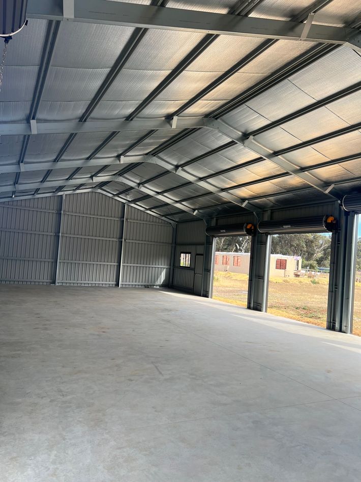 Interior of a large, empty metal building with insulated walls and roof and a concrete floor.