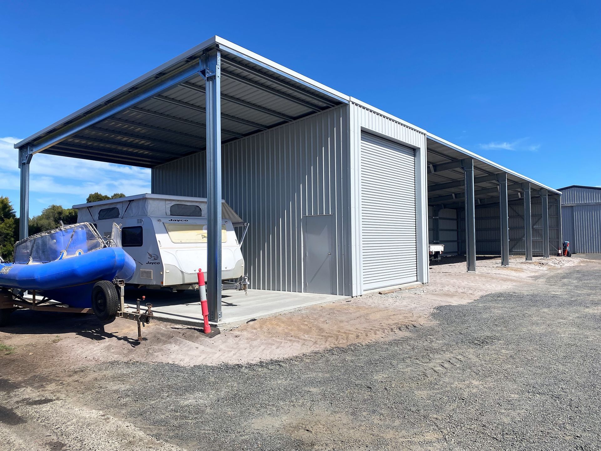 Steel sheds in a row on a green lawn with a cloudy blue sky.