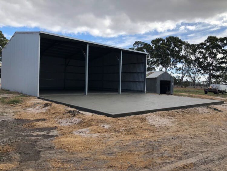 A large shed is sitting on top of a dirt field.