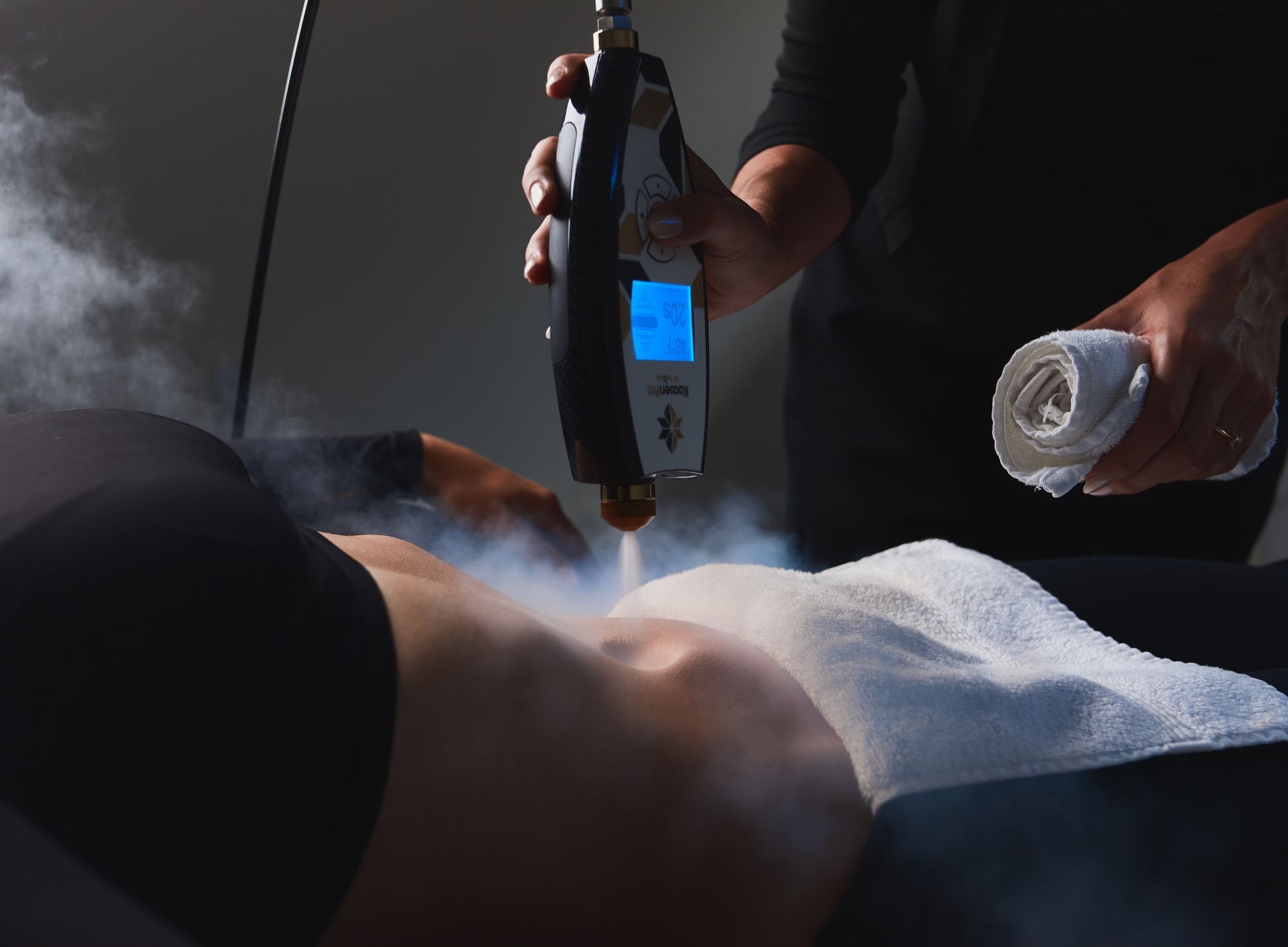 Person receiving cryotherapy treatment on abdomen; device emitting cold vapor.
