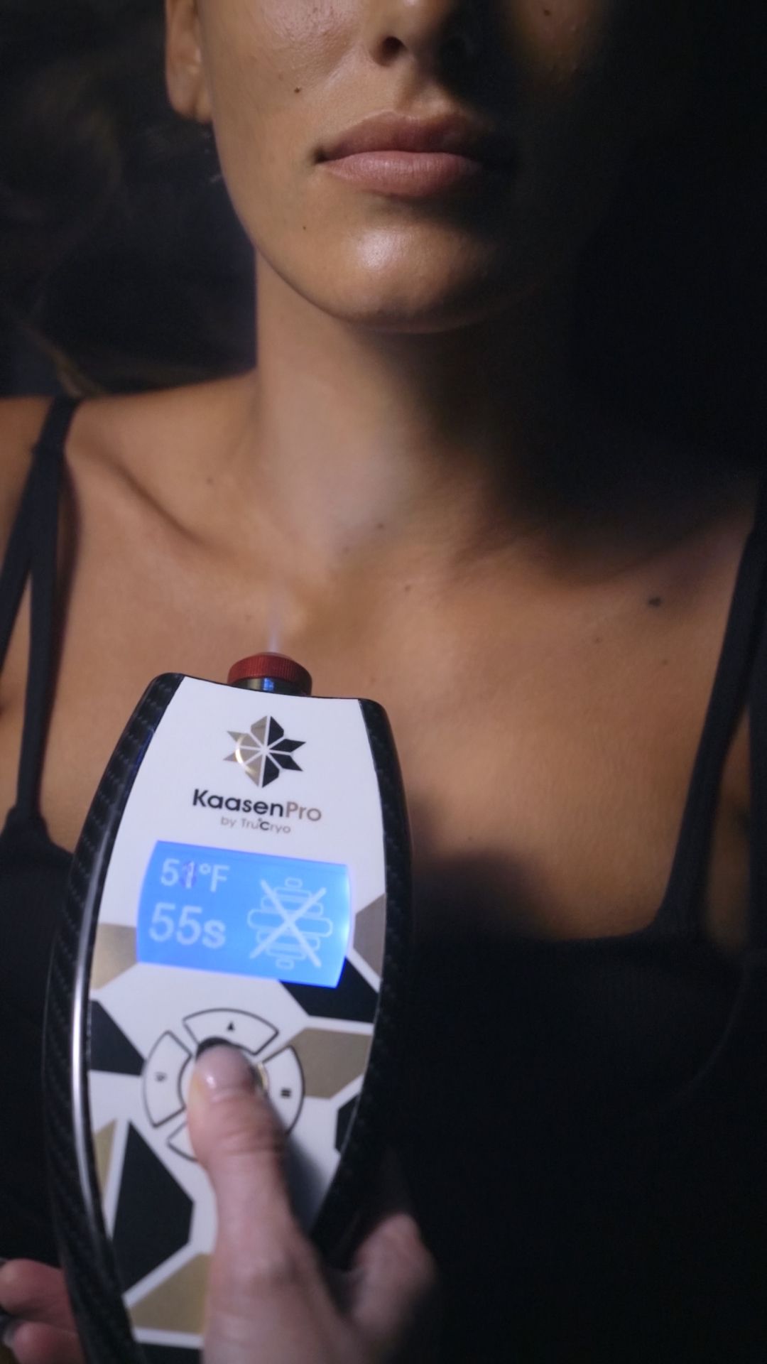 Woman holding a device to her neck. The device displays a temperature reading.