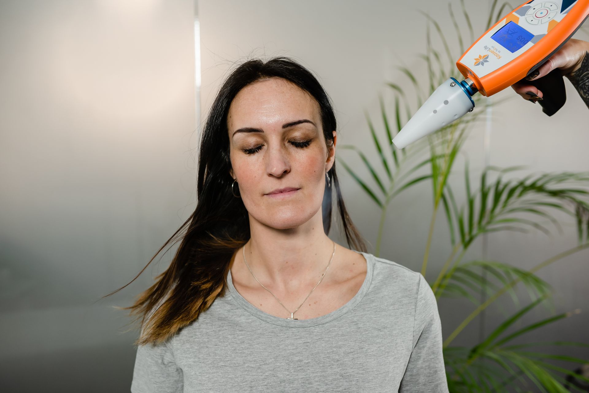 Woman with device pointed towards her head; interior shot.