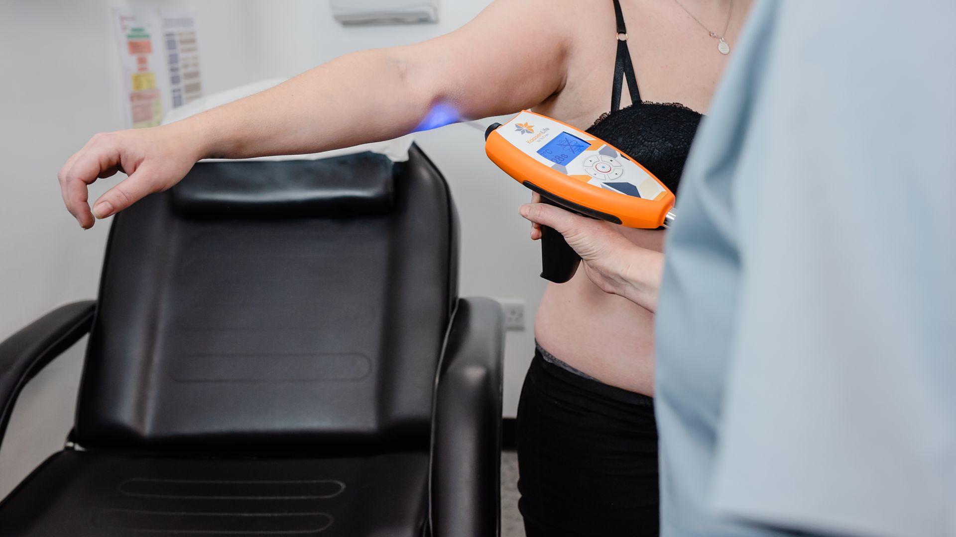 Person receiving light therapy on their arm in a doctor's office.