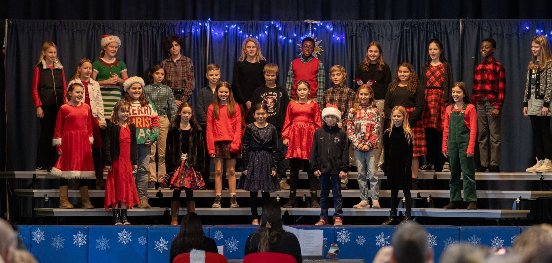 A large group of children are singing on a stage.