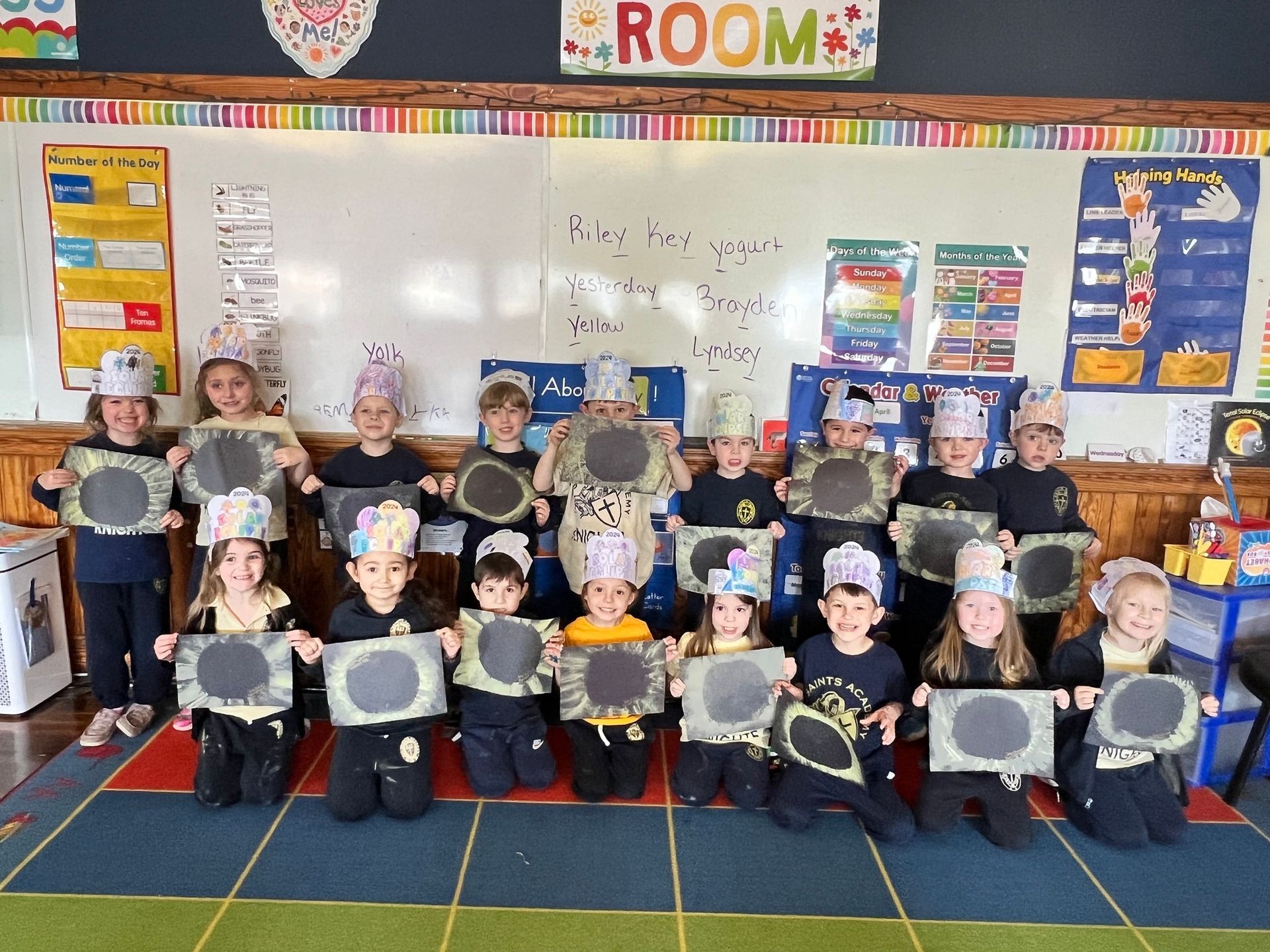 A group of children are posing for a picture in front of a room sign