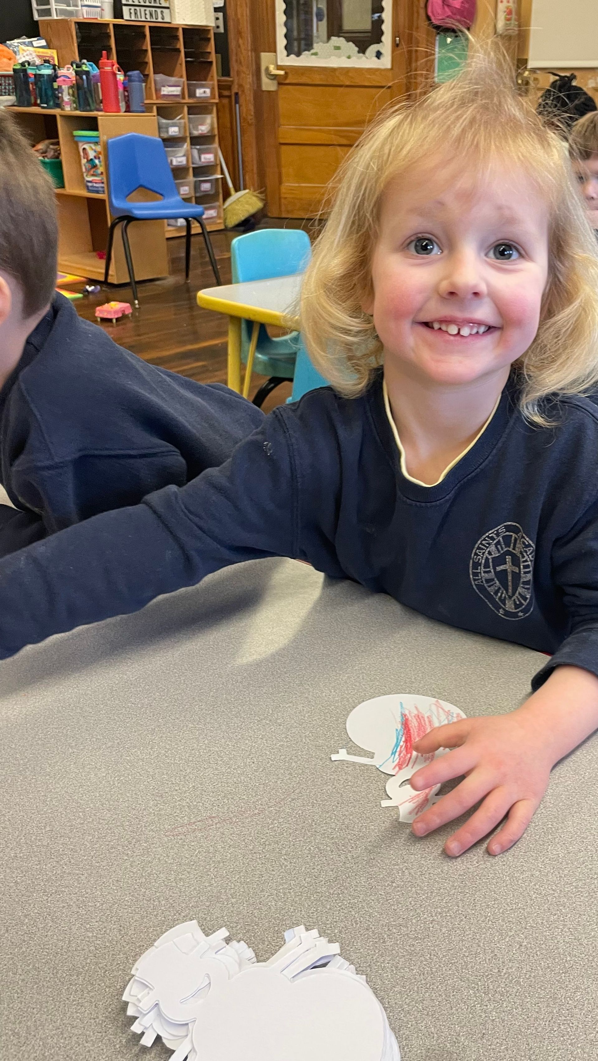 A little girl is smiling while sitting at a table