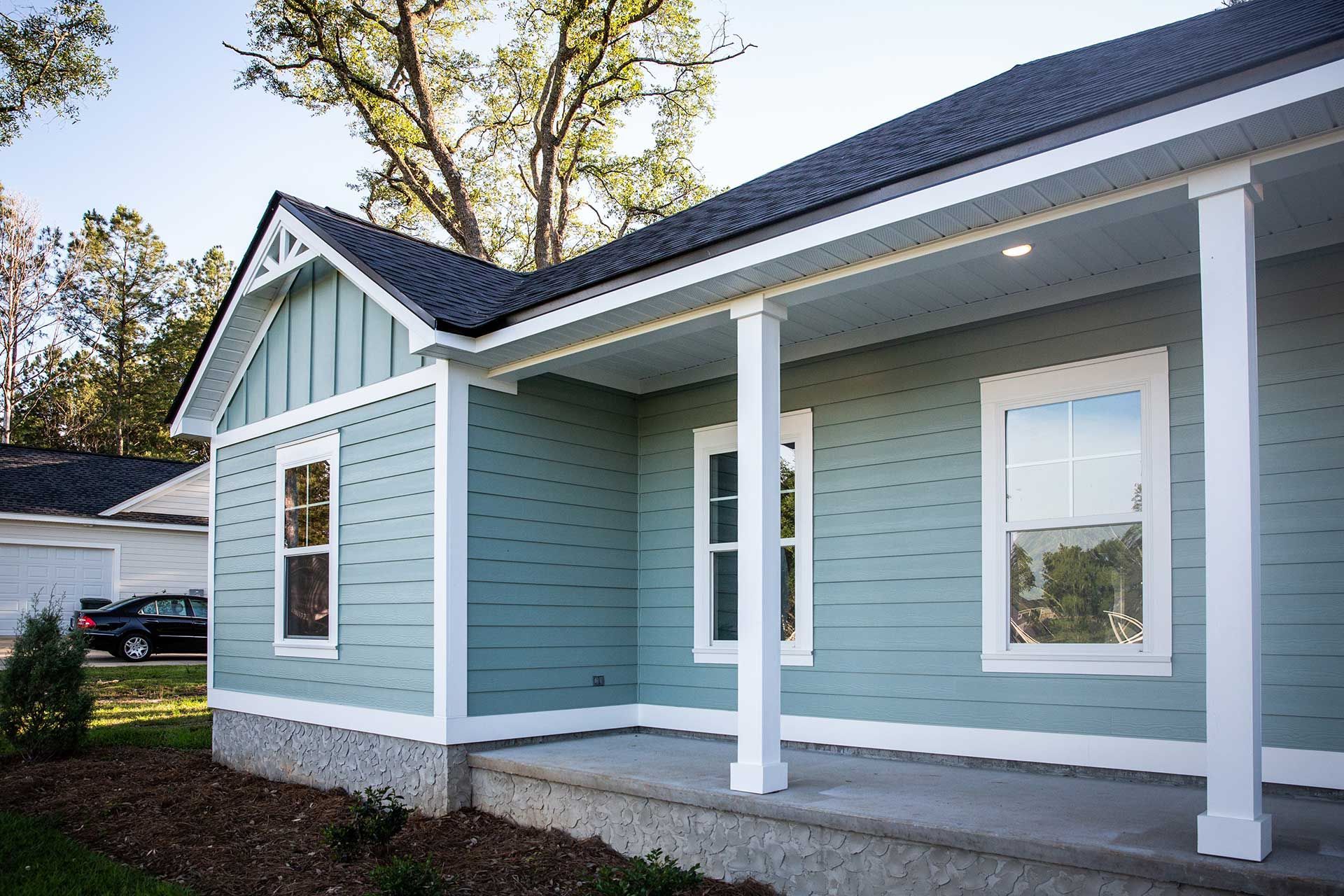 Front view of a brand new construction house with blue siding, a ranch style home with a yard
