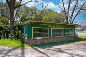 Green-painted building with large windows and a sign reading