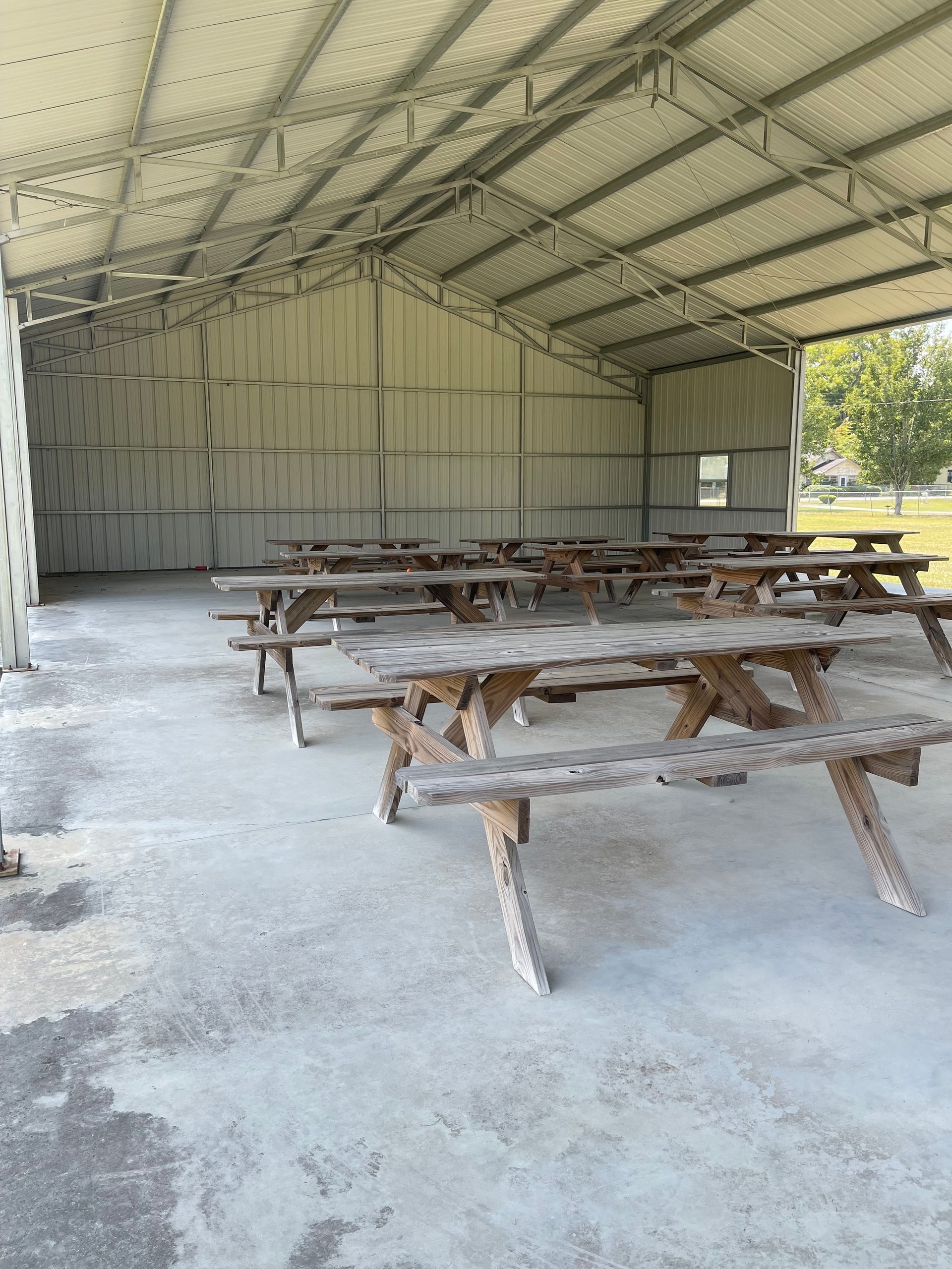 Picnic tables under a metal-roofed shelter in a park.