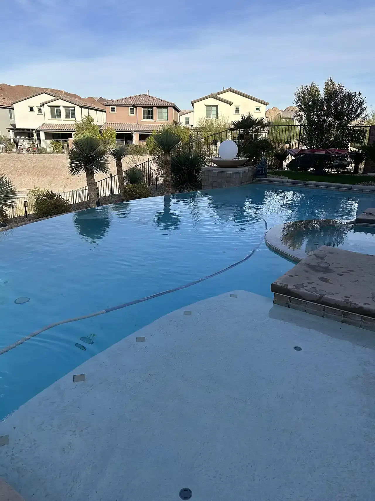 A large swimming pool in a residential area with houses in the background.