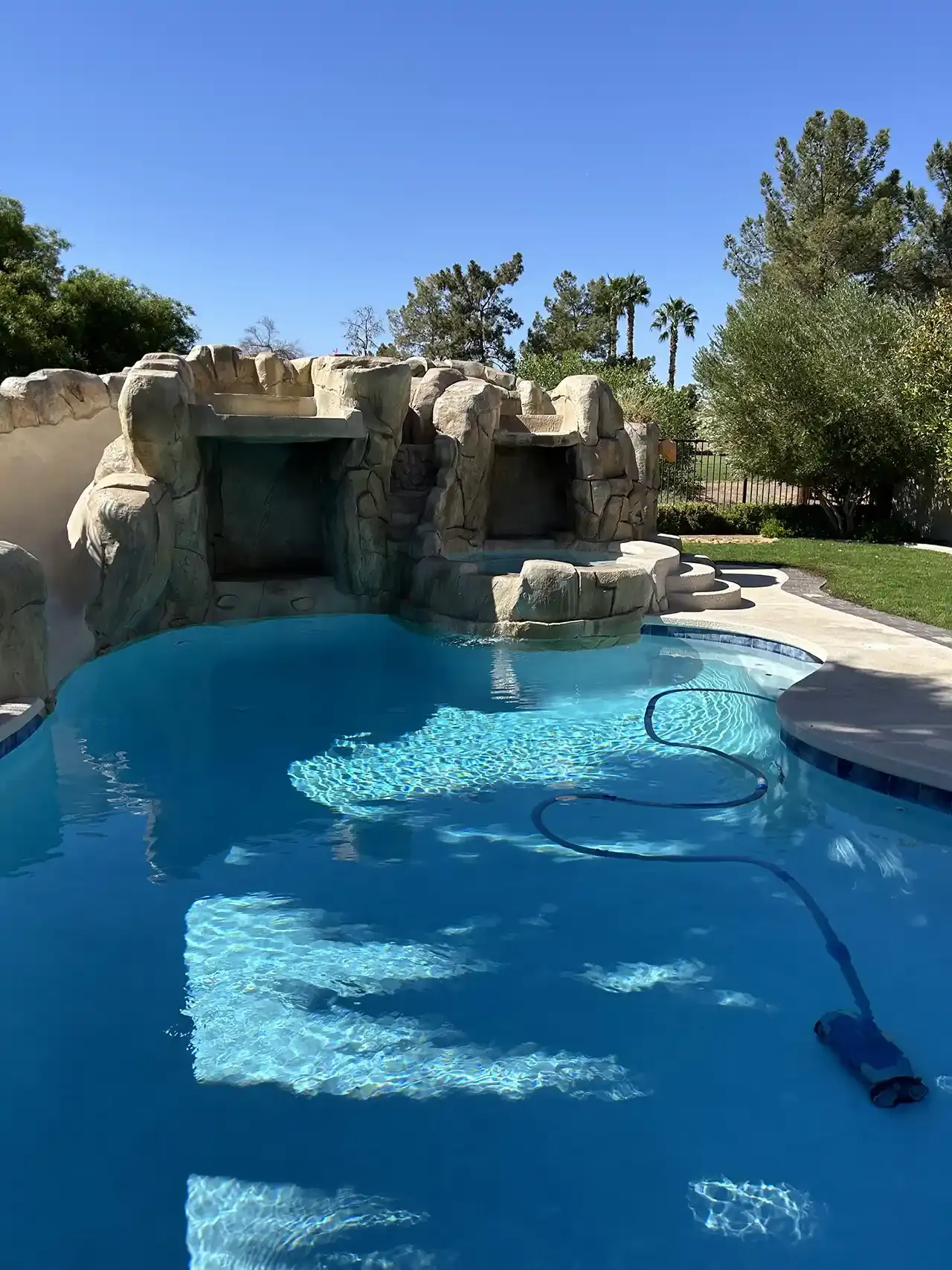 A large swimming pool with a waterfall in the background.