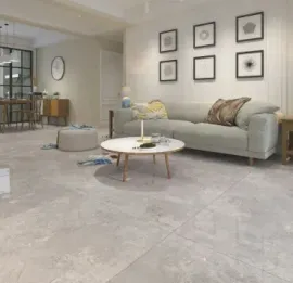 Living room with gray sofa, coffee table, and framed art. Dining area visible in the background.