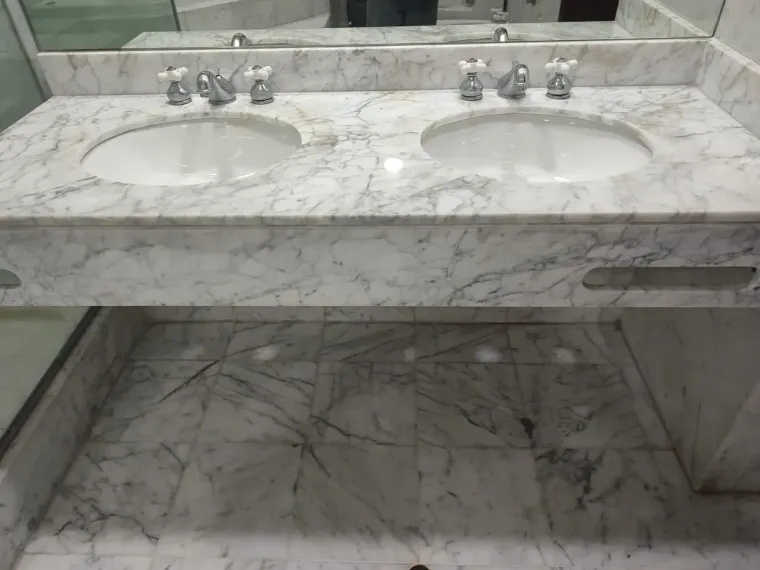 Marble bathroom vanity with two sinks and matching tiled floor.