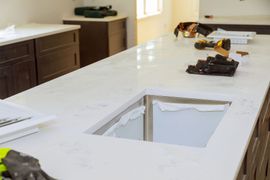 Kitchen countertop with a rectangular cutout, surrounded by cabinets and tools.