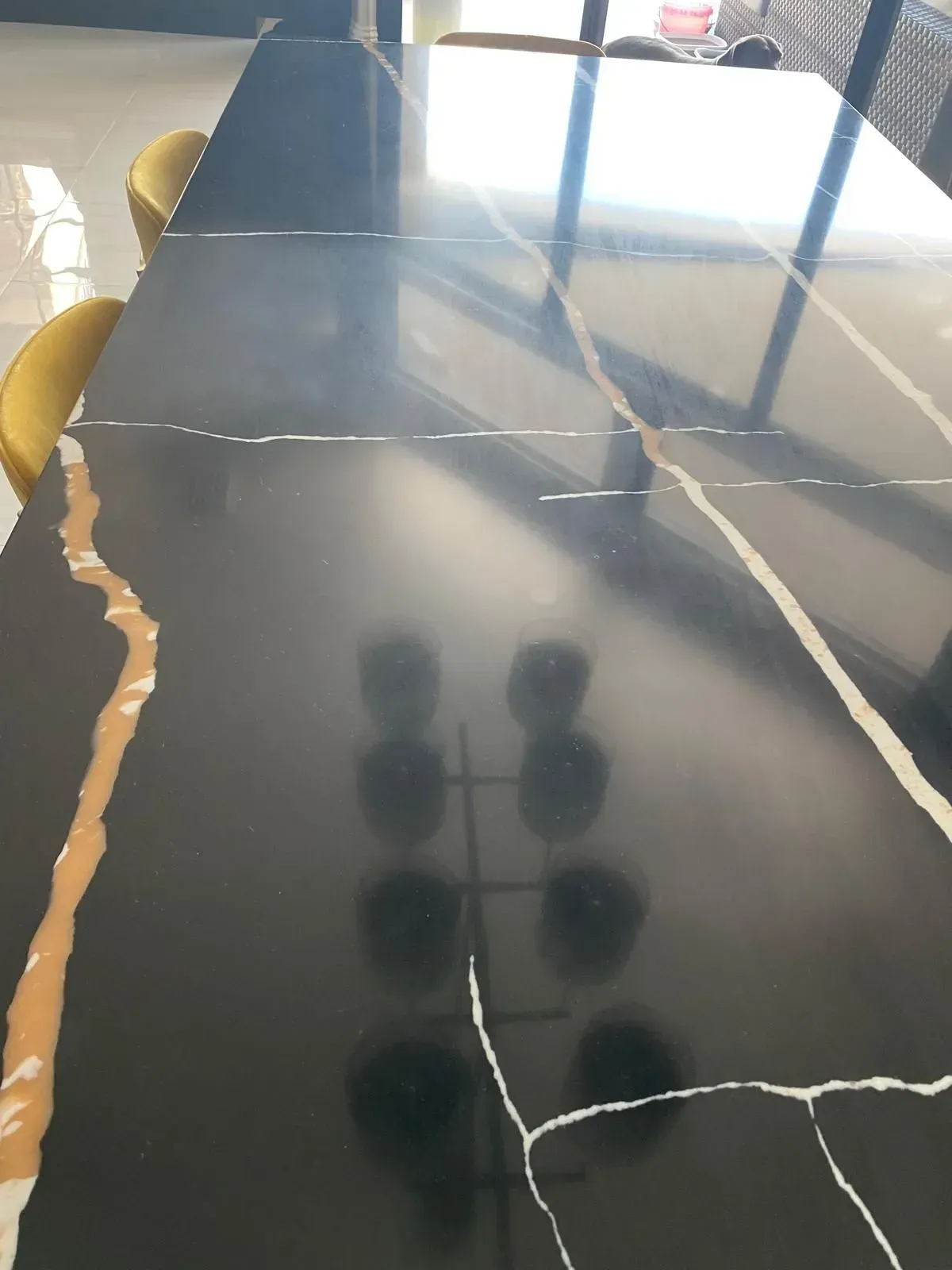Black rectangular table with gold and white veining, reflective surface.