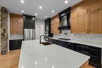 Modern kitchen with black and wood cabinets, white countertops, and a large island.