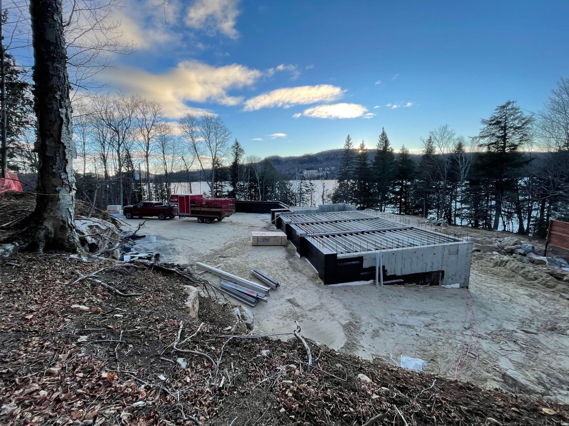Un chantier de construction dans les bois avec un lac en arrière-plan.