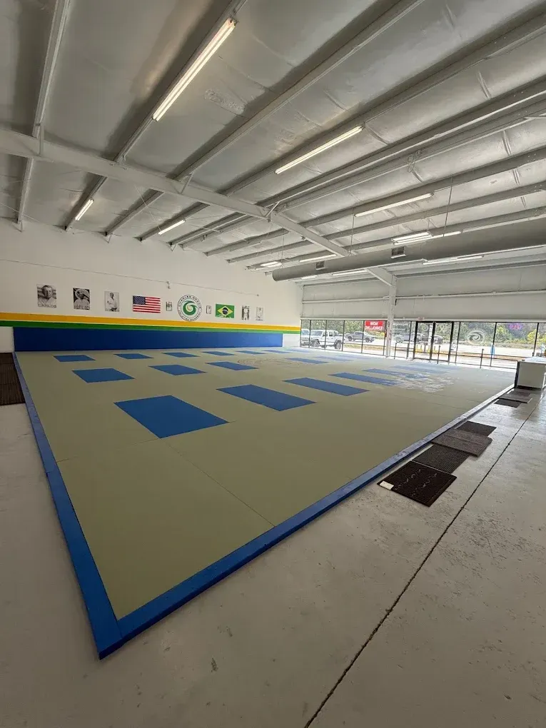 Inside at Charles Gracie Jiu Jitsu Magnolia with blue and tan mats, white walls, and a large open space.