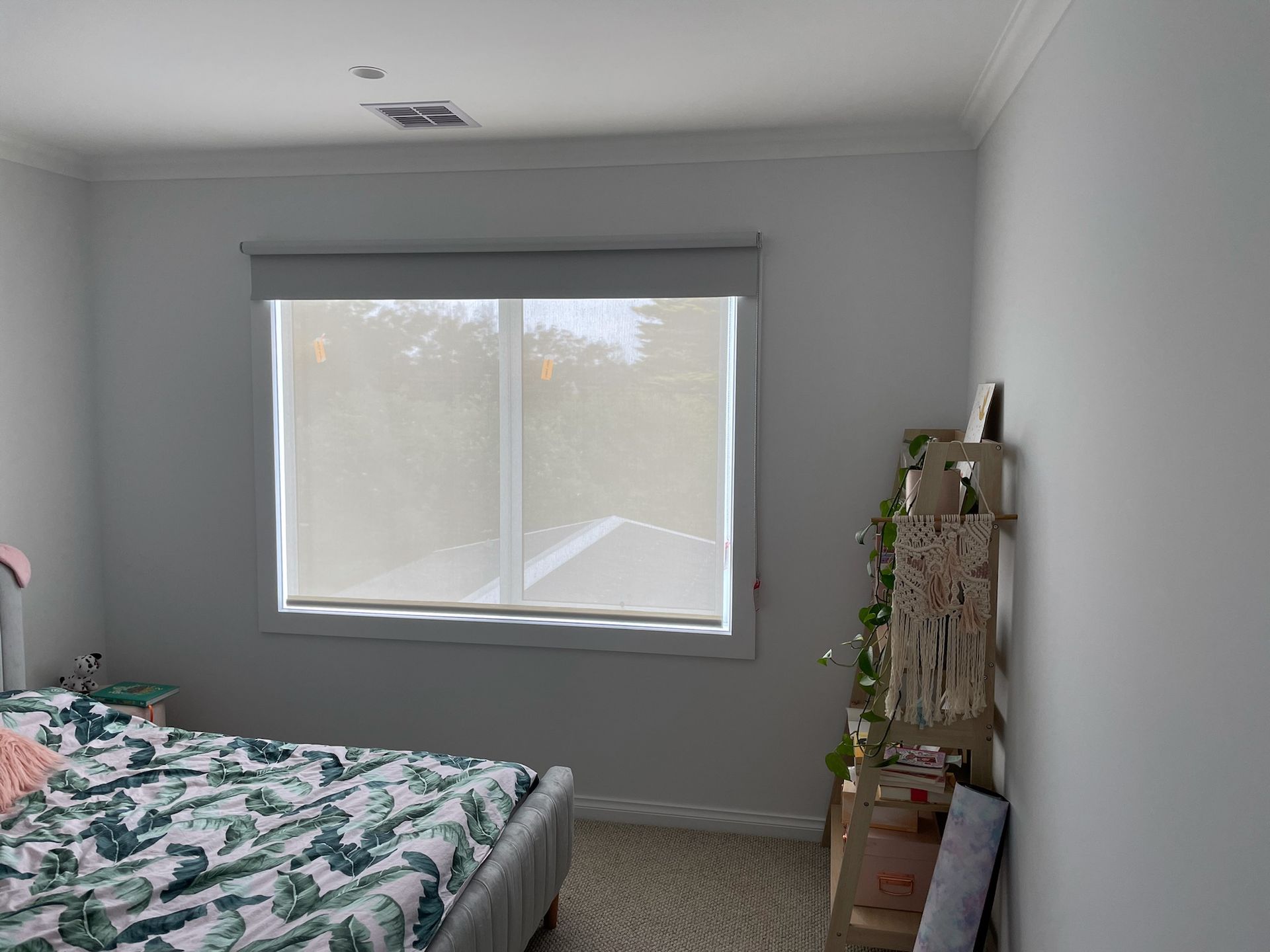 Minimal bedroom with a bed, window, and small plant shelf.