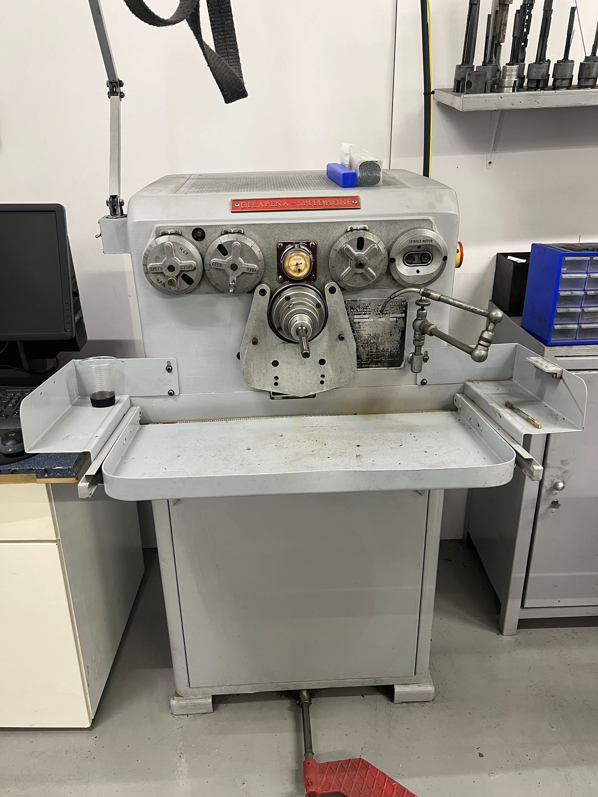 A light gray industrial drill sharpener machine standing on a workshop floor.