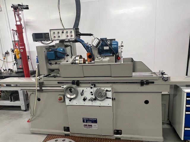 A light gray industrial cylindrical grinding machine situated in a clean workshop setting.