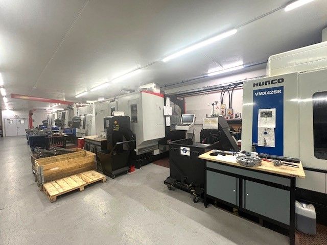A black metal cart holding a collection of various CNC milling machine tool holders and cutting tools on red stands.