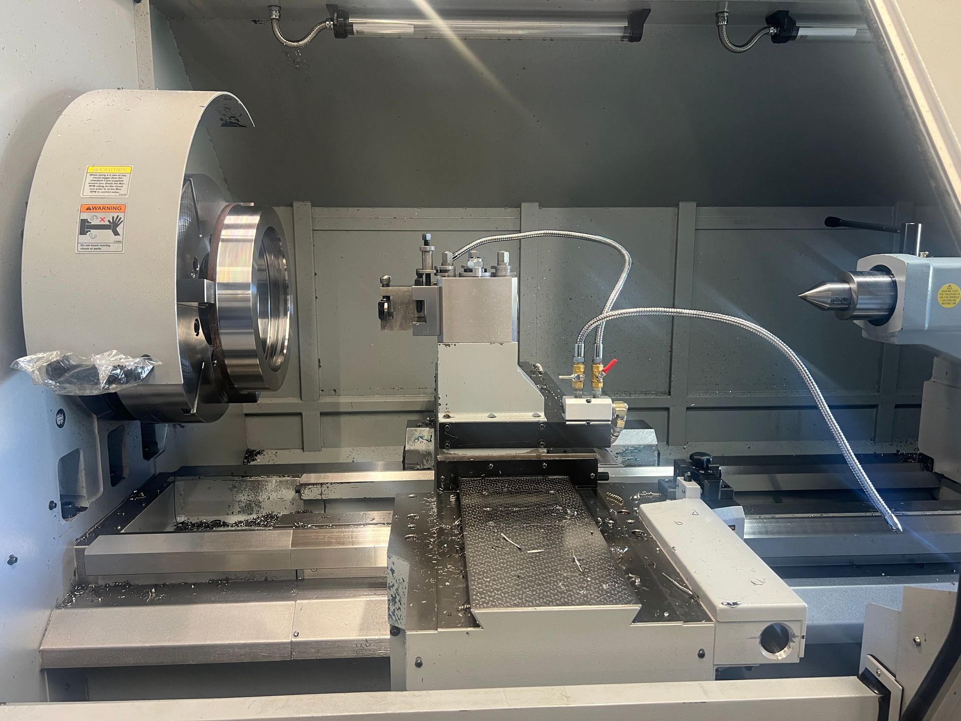 A CNC milling machine control panel with a screen showing a circular part diagram, positioned next to the machining area.