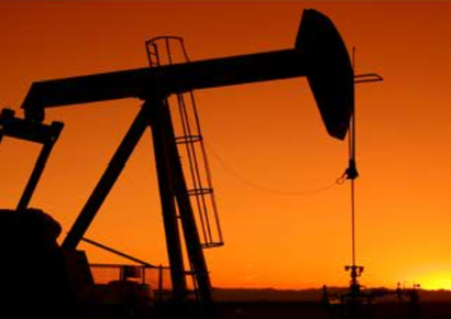 Silhouetted oil pumpjack at sunset against an orange sky