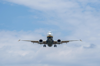 Airplane landing head-on against a cloudy blue sky