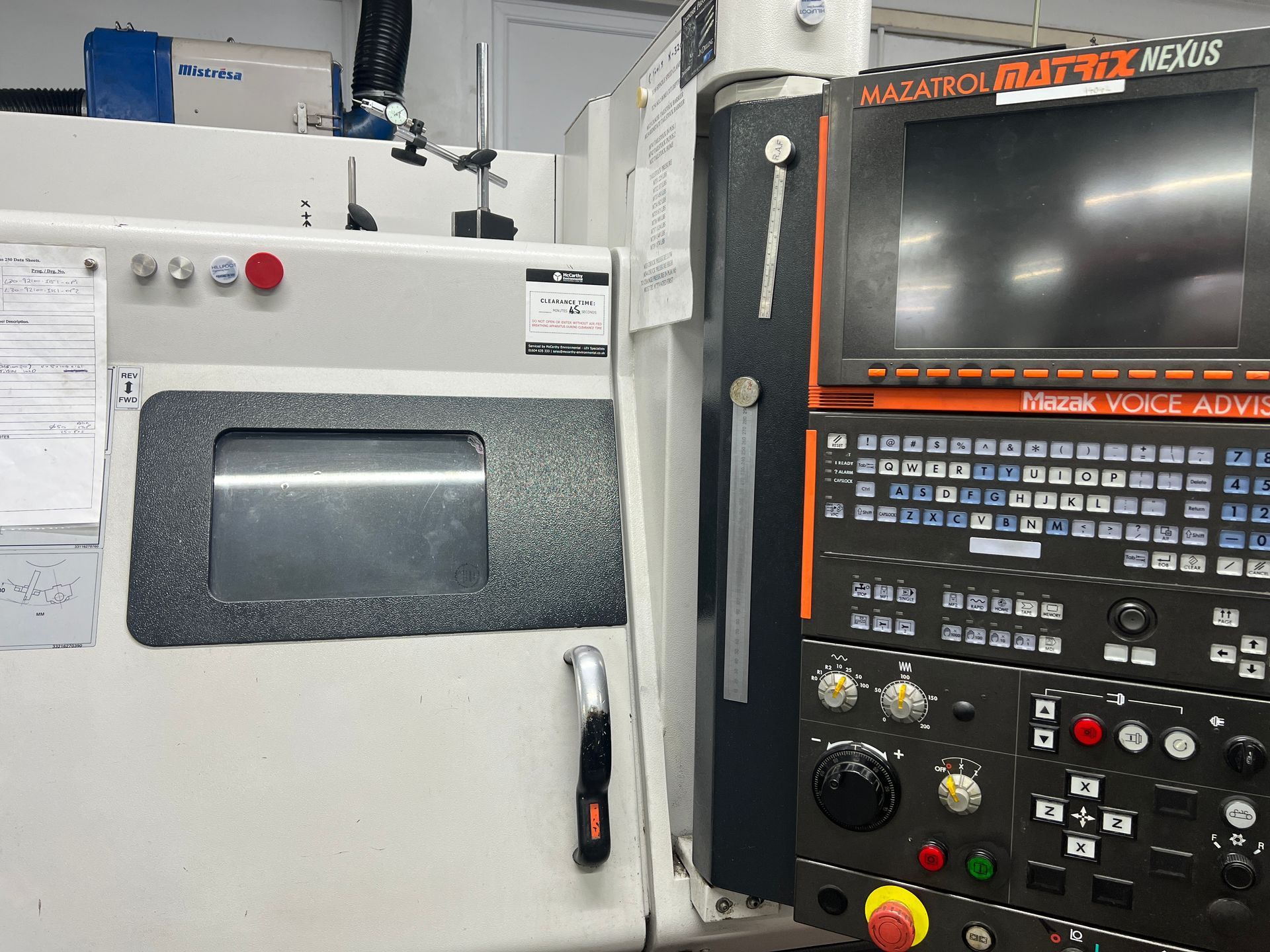 A Mazak Matrix CNC machine control panel with a digital display, tactile buttons, and a mechanical work window.