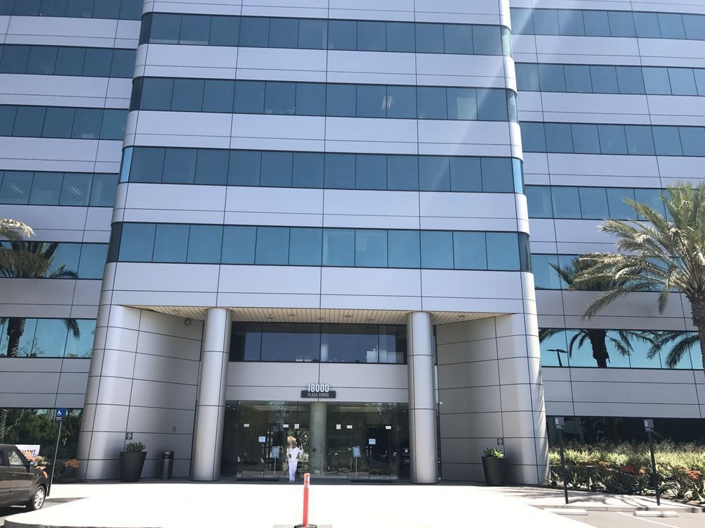 Modern glass office building entrance with columns and palm trees