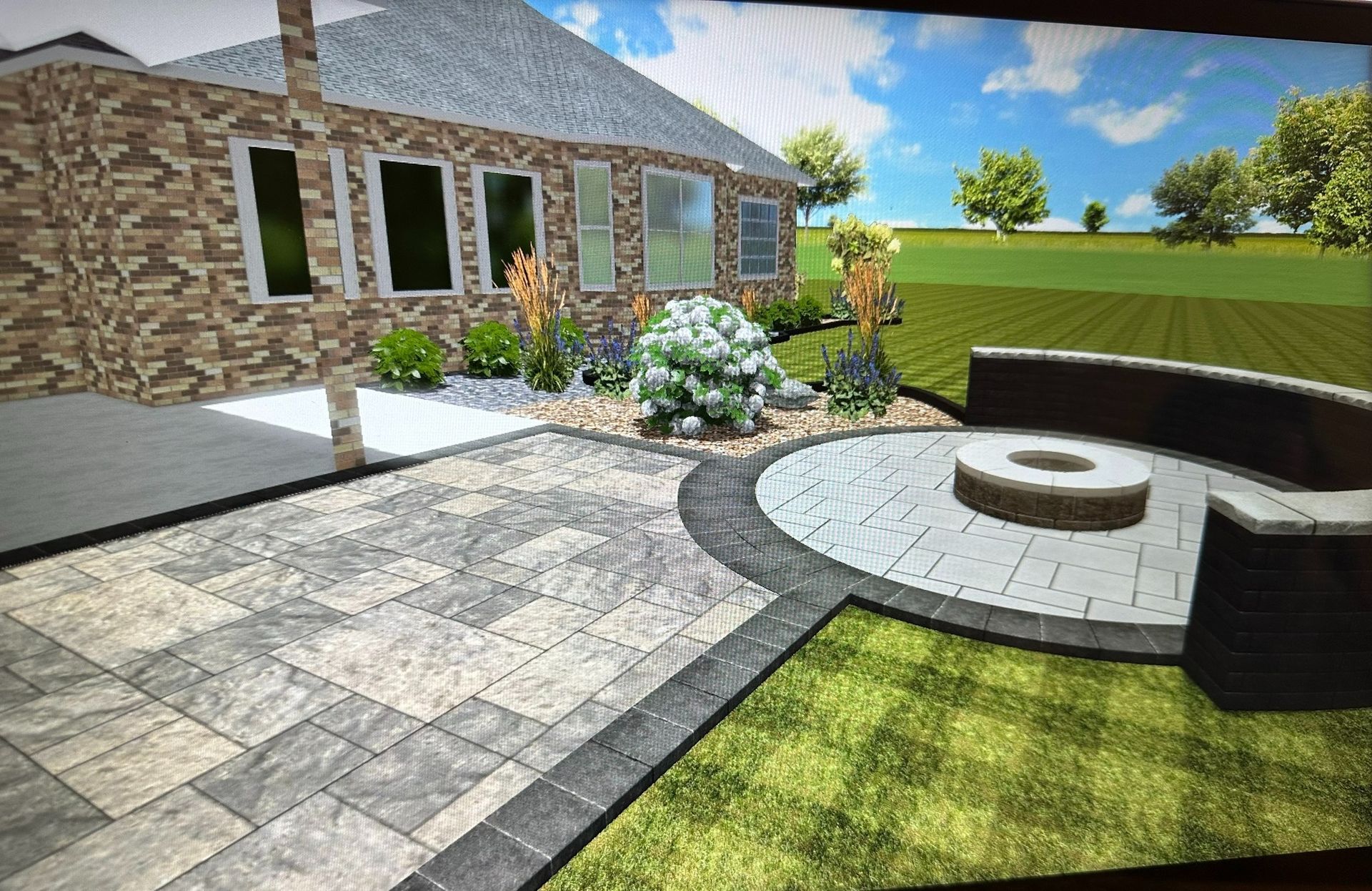 A digital landscape rendering shows a stone house exterior with a paved patio, a circular fire pit area, and lawn.