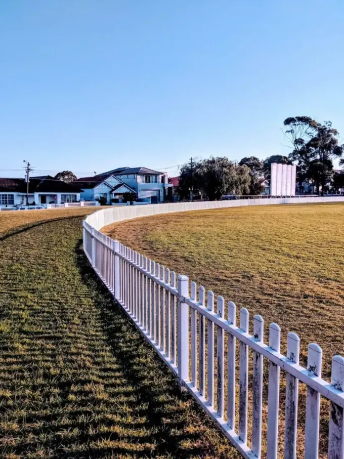 A white picket fence surrounds a grassy field.