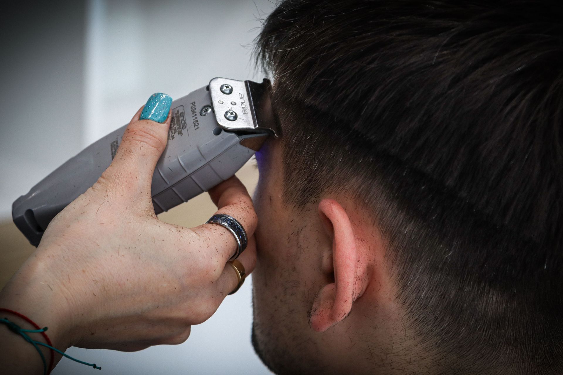 Barber cutting the back and side of a man’s hair with clippers