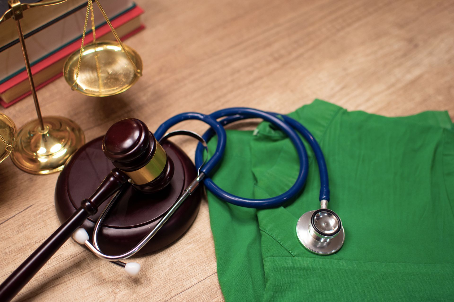 Gavel, stethoscope, and justice scales on table with green scrubs.