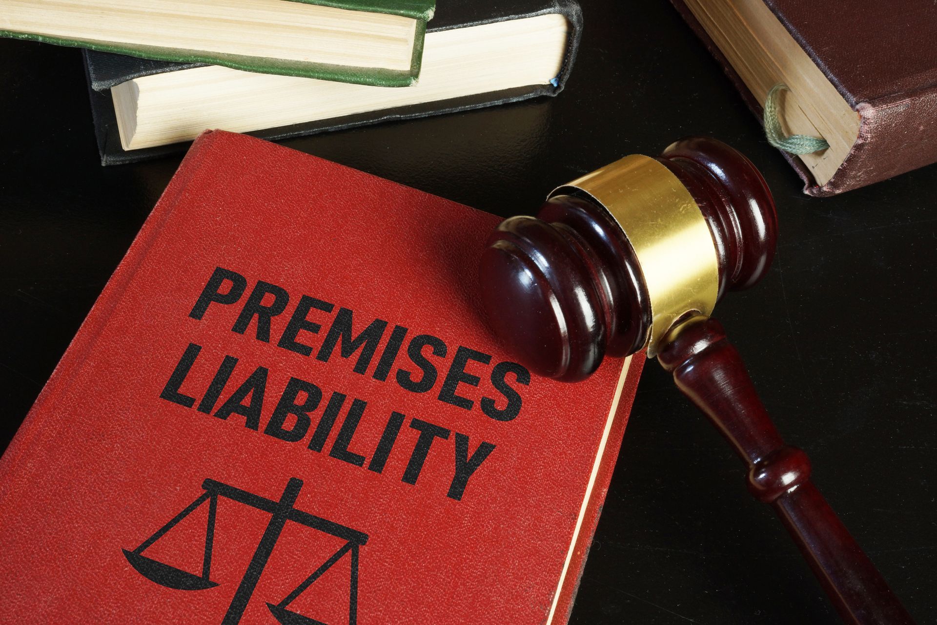 Close-up of a premises liability law book with a wooden gavel resting on top near other books.