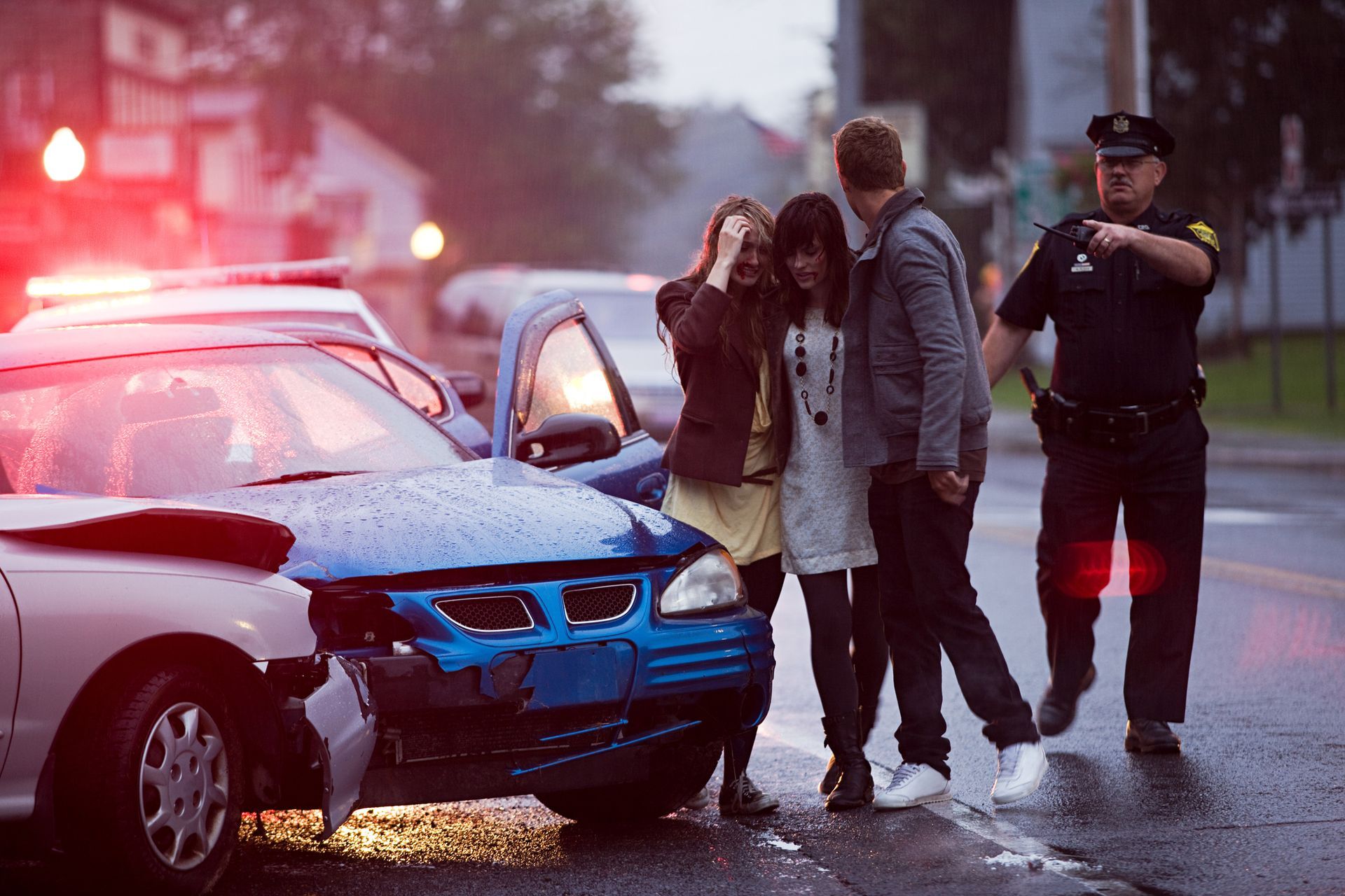 Young people and a police officer at the scene of a car crash.
