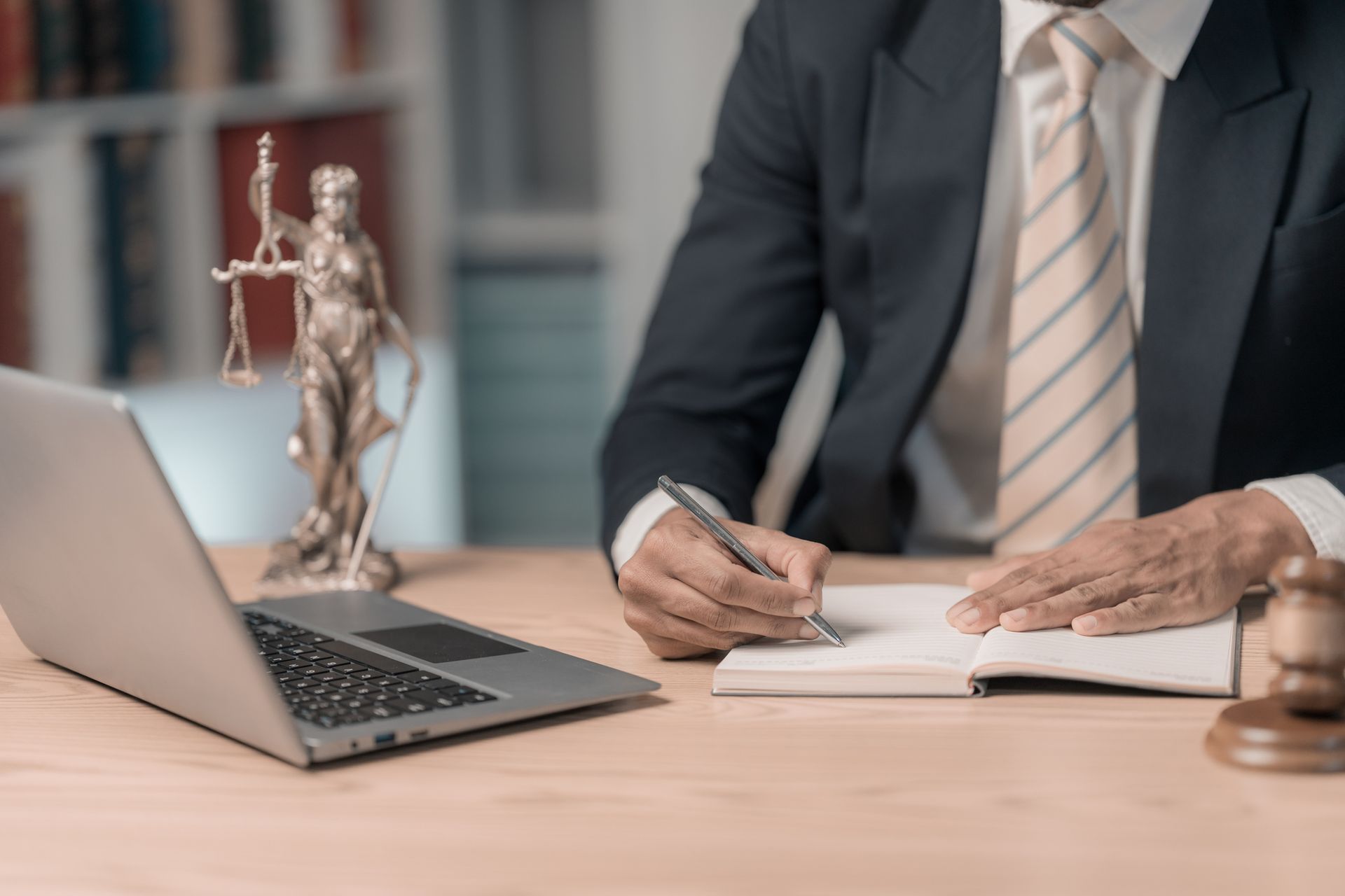 Lawyer in suit reviewing and signing legal documents with justice scale on the table nearby