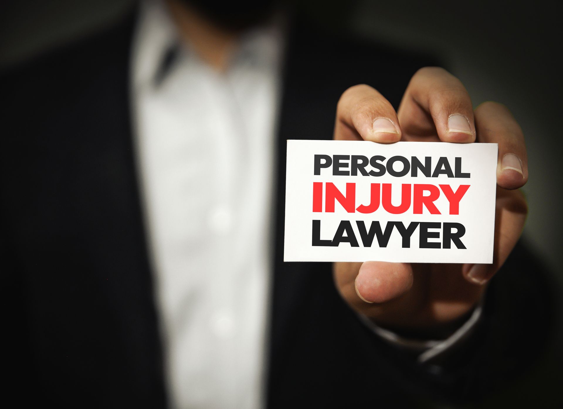 Person holds card reading PERSONAL INJURY LAWYER. 